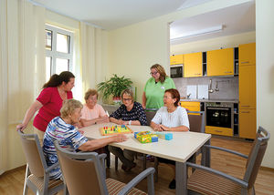 Eine Gruppe Senioren spielt Mensch, ärgere dich nicht in der Wohnküche der Senioren-WG