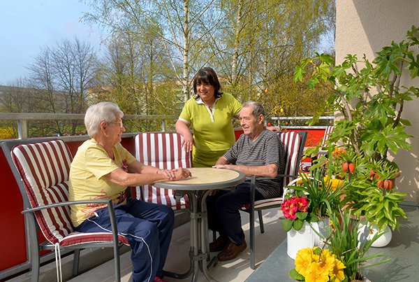 Senioren mit Pflegekraft auf dem Balkon der Senioren-WG Barlachstraße